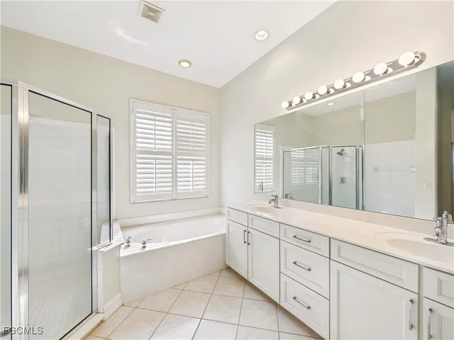 a spacious bathroom with a double vanity sink a large mirror and a bathtub with shower