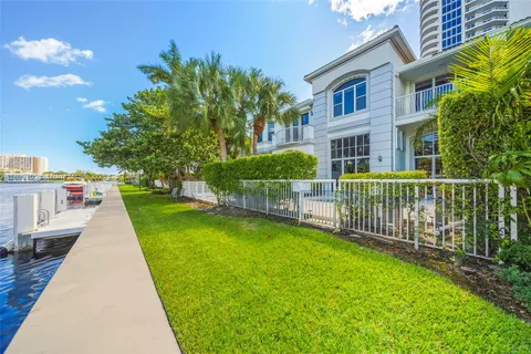 a large kitchen with granite countertop a stove top oven a refrigerator a sink dishwasher and white cabinets