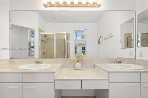 a bathroom with a tub a double vanity sink a window and a mirror