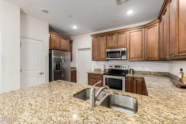 a kitchen with granite countertop a stove top oven a sink dishwasher a refrigerator and a microwave