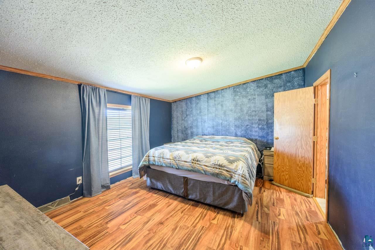 3201 Wilderness Road Makinen, MN 55763 - Photo 10 of 44 Wood-finish flooring, textured accent wall, window with blinds, overhead lighting fixture, and a solid core door