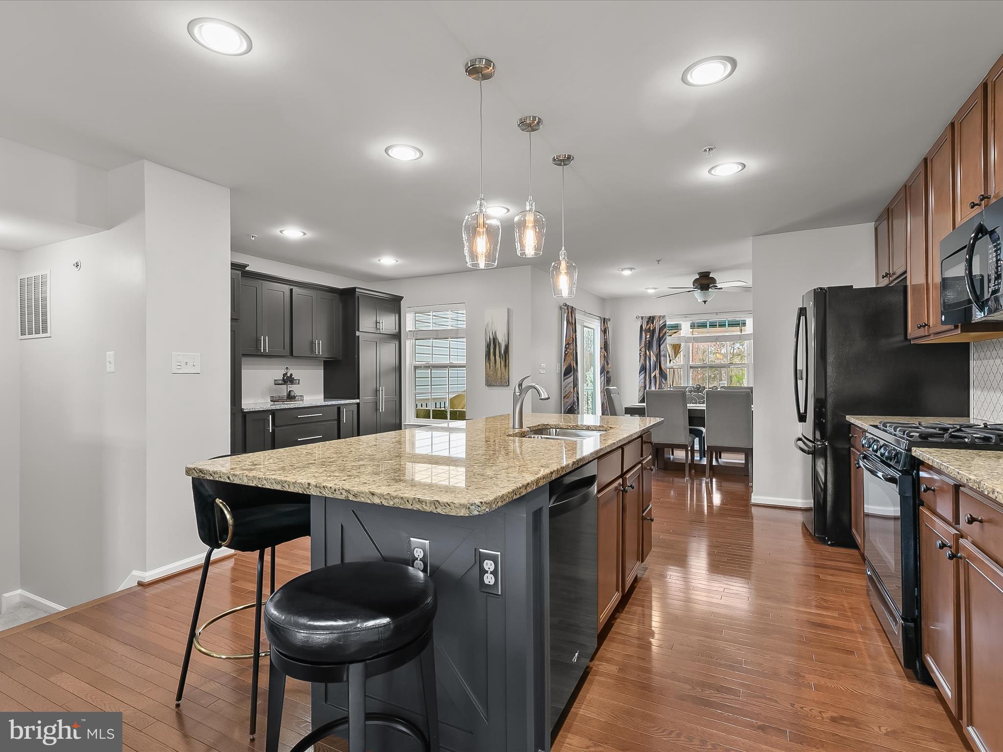 1410 Wellspring Drive Aberdeen, MD 21001 - Photo 15 of 55 a kitchen with stainless steel appliances kitchen island granite countertop a table chairs in it and wooden floors
