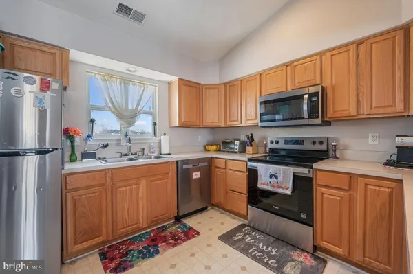 a kitchen with stainless steel appliances granite countertop a sink stove refrigerator and cabinets