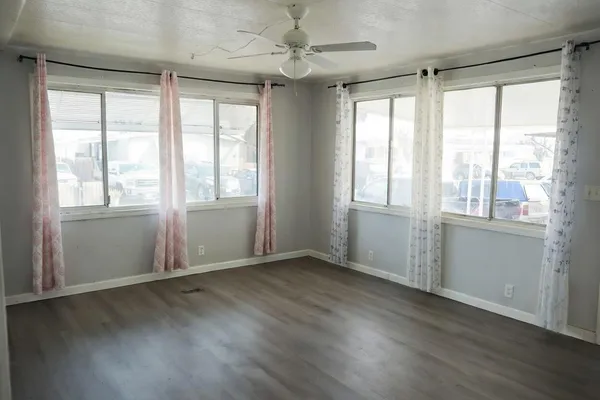 a view of an empty room with wooden floor and a window