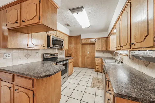 a large kitchen with granite countertop lots of white cabinets a sink and dishwasher a stove with wooden cabinets