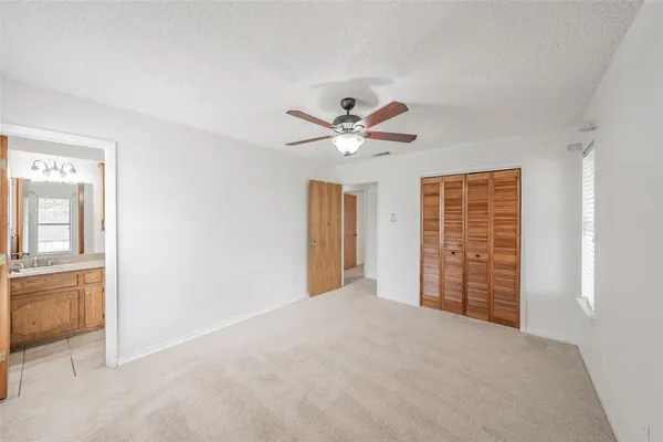 a view of an empty room with a ceiling fan and window