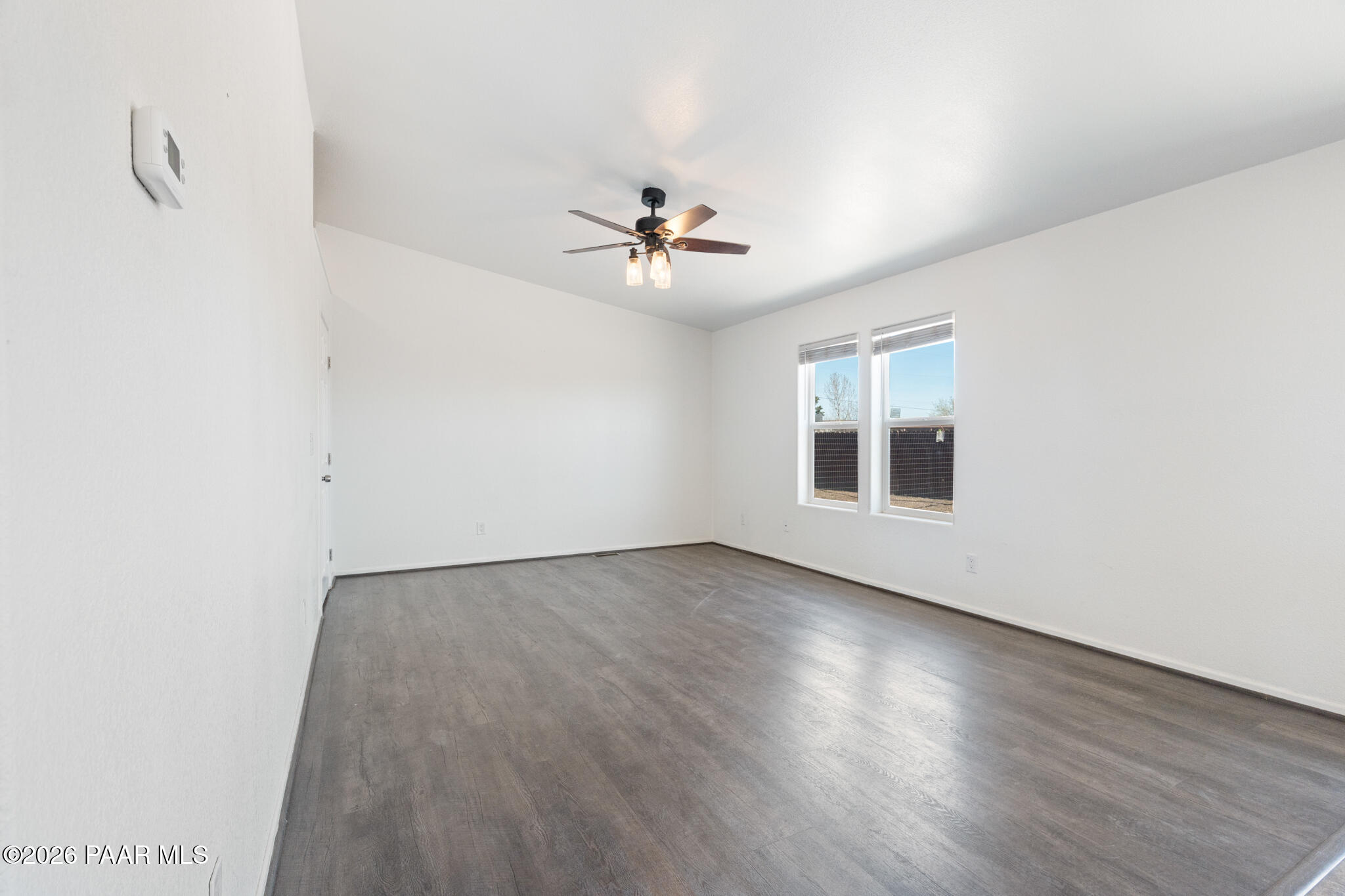 575 Ranch House Road Paulden, AZ 86334 - Photo 11 of 36 an empty room with wooden floor ceiling fan and windows