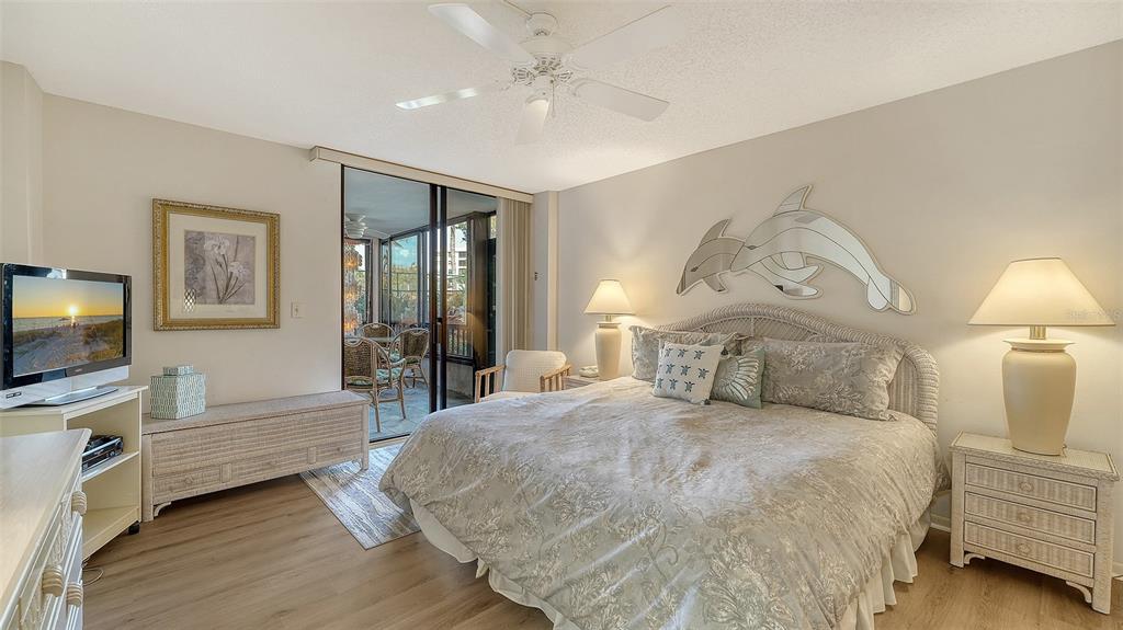8773 Midnight Pass Road, Unit 102G Sarasota, FL 34242 - Photo 23 of 79 a spacious bedroom with a bed and a flat screen tv