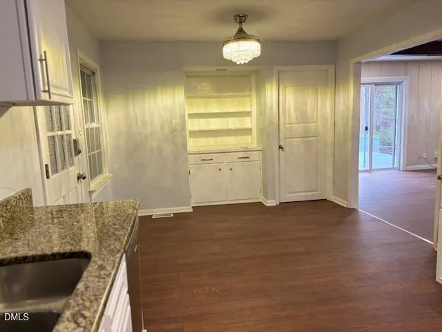 an empty room with wooden floor fireplace and windows