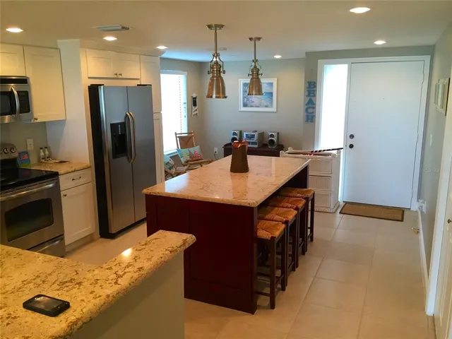 a kitchen with stainless steel appliances granite countertop a sink a kitchen island a stove and a refrigerator