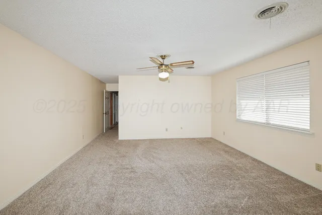 an empty room with window and ceiling fan