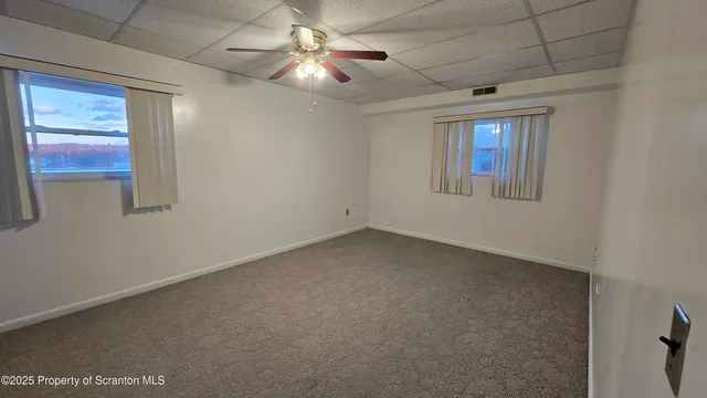 an empty room with windows and fan