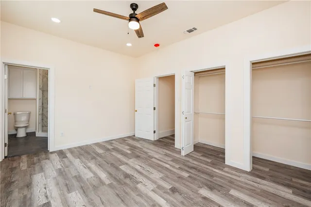 an empty room with wooden floor and ceiling fan