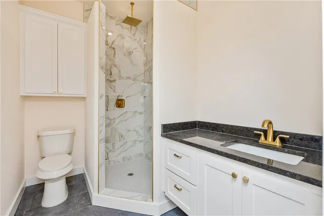 a bathroom with a granite countertop sink a toilet and shower