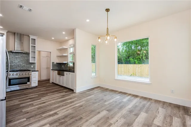 a view of an empty room with kitchen and window