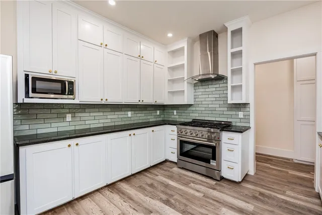a kitchen with granite countertop white cabinets stainless steel appliances and wooden floor