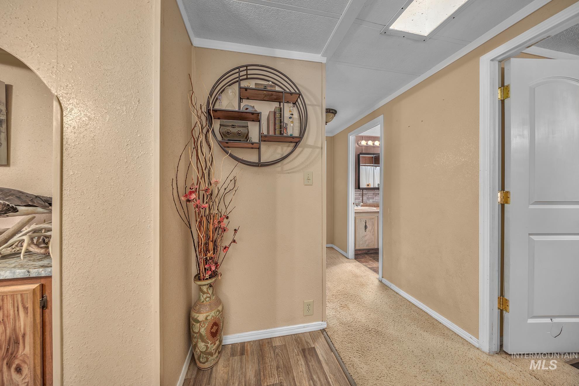 1165 Pioneer Road Weiser, ID 83672 - Photo 12 of 24 Hallway with wood finished floors, a textured wall, and crown molding