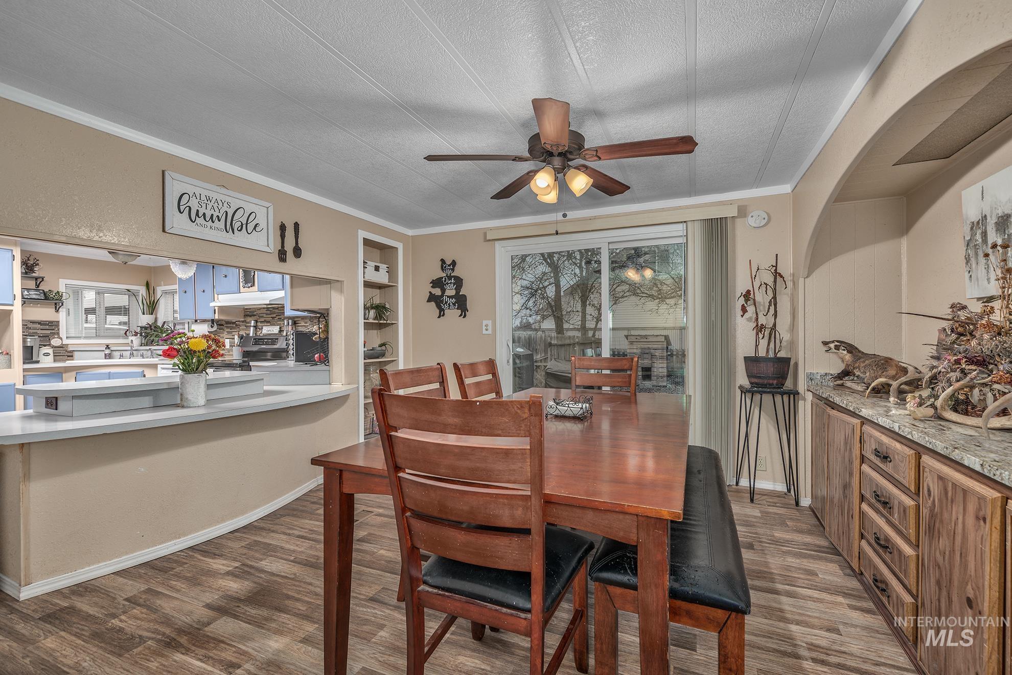 1165 Pioneer Road Weiser, ID 83672 - Photo 13 of 24 Dining space featuring dark wood finished floors, ornamental molding, a ceiling fan, a textured ceiling, and built in shelves
