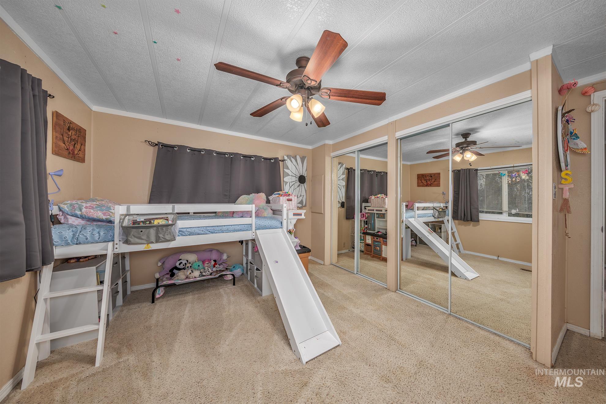 1165 Pioneer Road Weiser, ID 83672 - Photo 22 of 24 Bedroom with multiple closets, light colored carpet, crown molding, and ceiling fan
