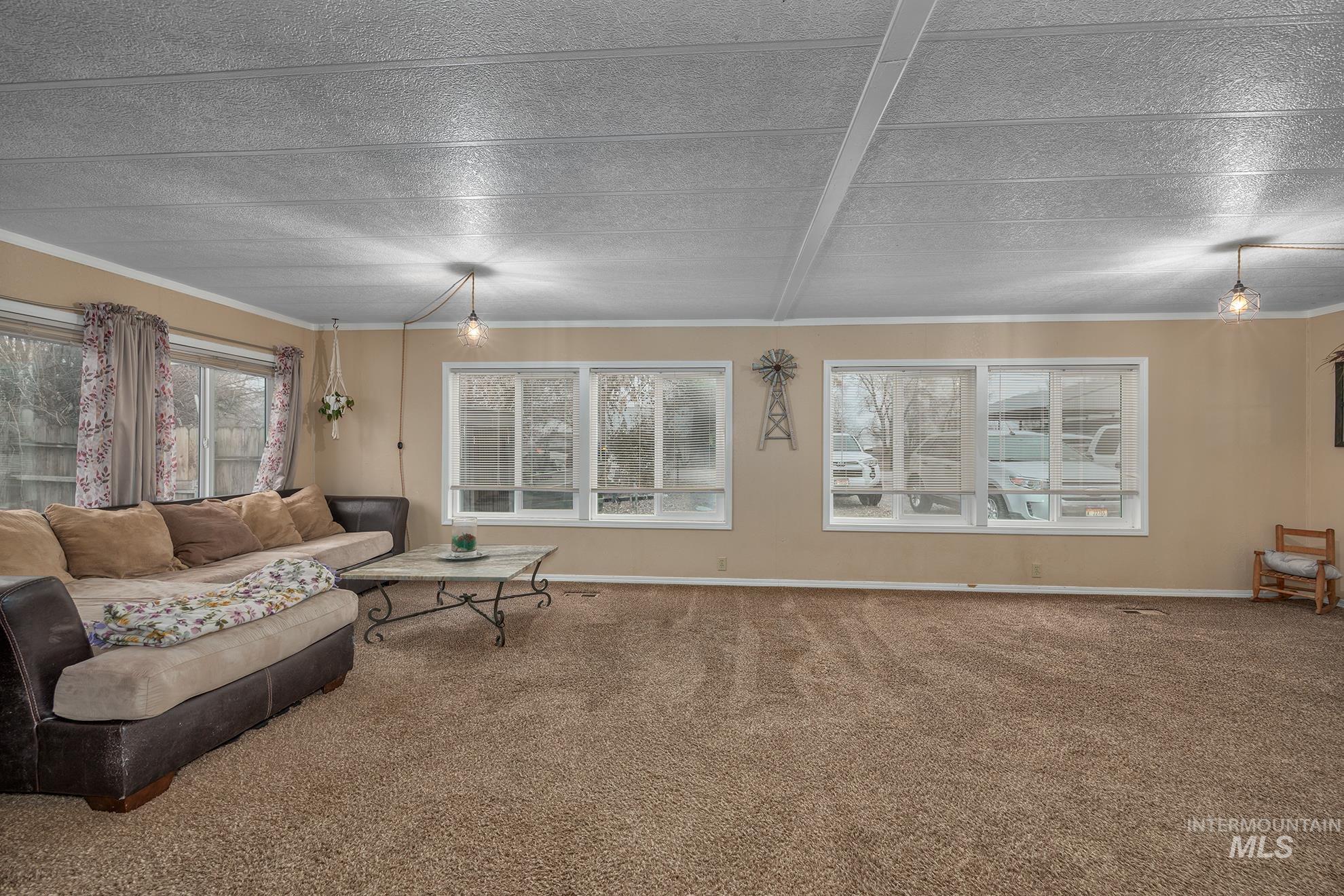 1165 Pioneer Road Weiser, ID 83672 - Photo 10 of 24 Carpeted living area featuring crown molding and baseboards