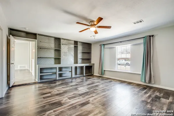 a view of a room with a ceiling fan and wooden floor