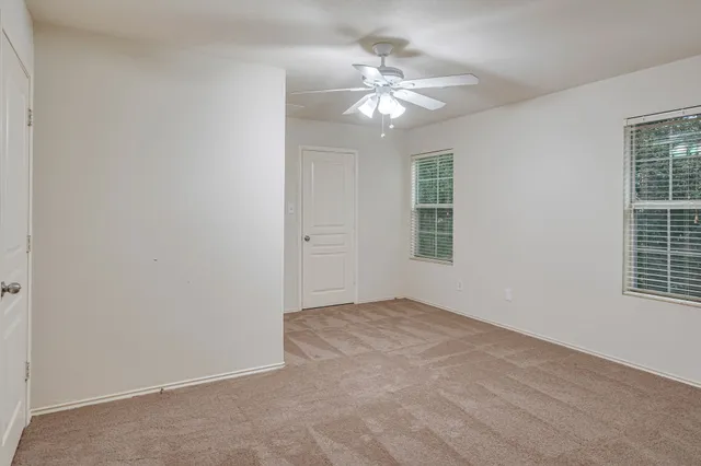 en empty room with windows and chandelier fan