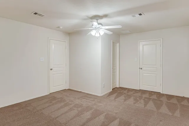 a view of an empty room and chandelier fan
