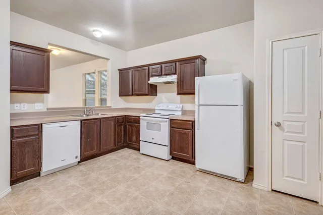 a kitchen with a white stove refrigerator and cabinets