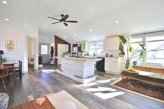 a living room with furniture appliances kitchen view and a dining table