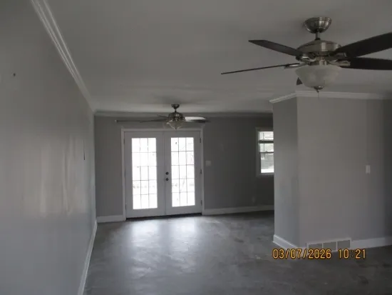 an empty room with windows and fan
