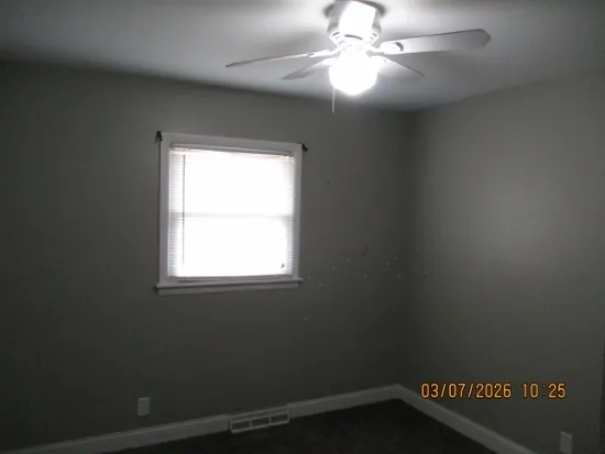 an empty room with a window and a fan