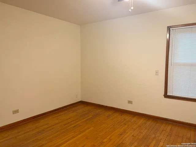 an empty room with wooden floor closet and windows