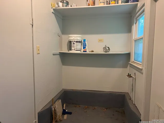 a room with water heater and storage racks on th wall