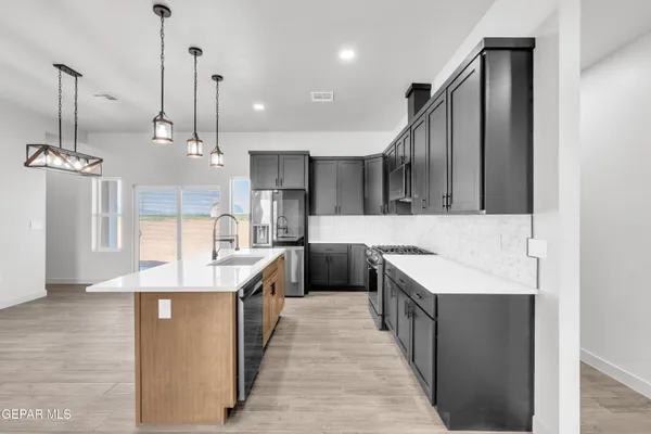 a kitchen with stainless steel appliances granite countertop a sink a stove and a refrigerator