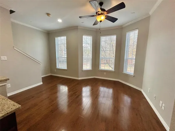 a view of an empty room with a window and wooden floor