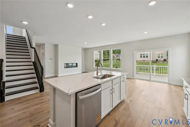 a view of a kitchen with a sink and dishwasher with wooden floor