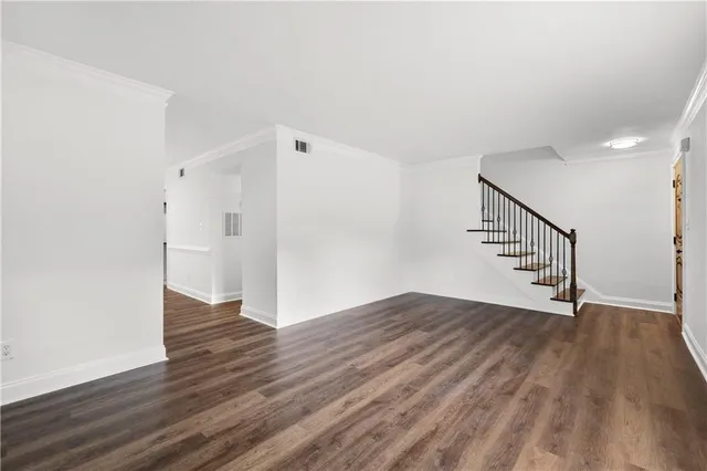 a view of an empty room with wooden floor and stairs