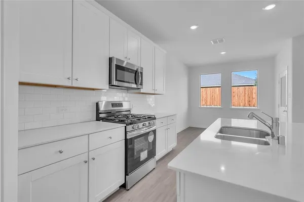 a kitchen with stainless steel appliances granite countertop a stove a sink and a microwave