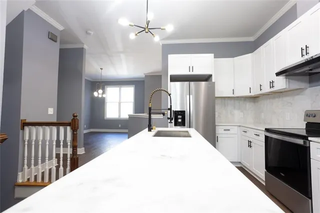 a kitchen with kitchen island stainless steel appliances a sink cabinets and wooden floor