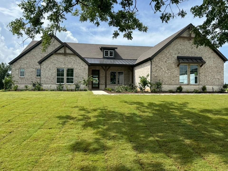 205 Cobb Road Leonard, TX 75452 - Photo 1 of 23 Stone facade residence featuring a covered entry porch, dark metal roof accents, multiple gables, and a dormer window