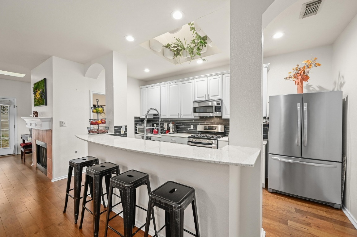 2721 Kinney Oaks Court Austin, TX 78704 - Photo 5 of 28 a kitchen with stainless steel appliances a refrigerator a stove a sink dishwasher and white cabinets with wooden floor
