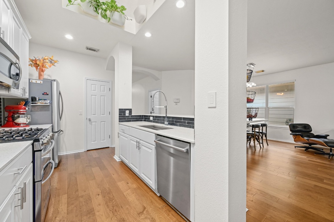 2721 Kinney Oaks Court Austin, TX 78704 - Photo 7 of 28 a kitchen with stainless steel appliances granite countertop a stove top oven a sink a dining table and chairs with wooden floor