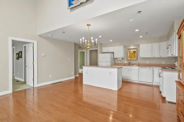 a large kitchen with granite countertop a stove top oven a sink dishwasher and white cabinets with wooden floor