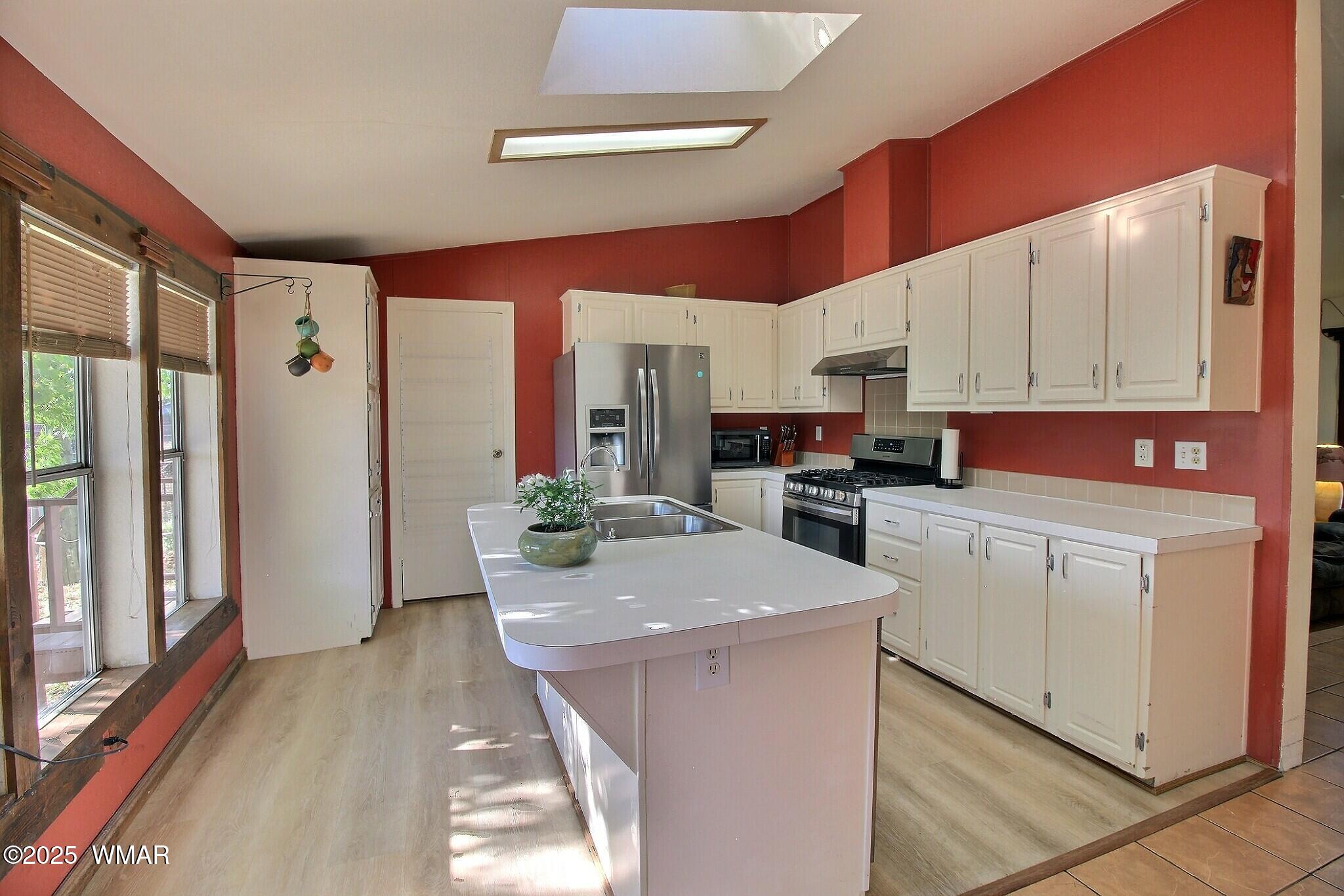 4134 Porter Mountain Road Lakeside, AZ 85929 - Photo 9 of 43 The kitchen area has large windows and sky lights for lots o natural light. The design provides a sense of privacy from the living room. An island features the sink that looks out towards the large back yard.