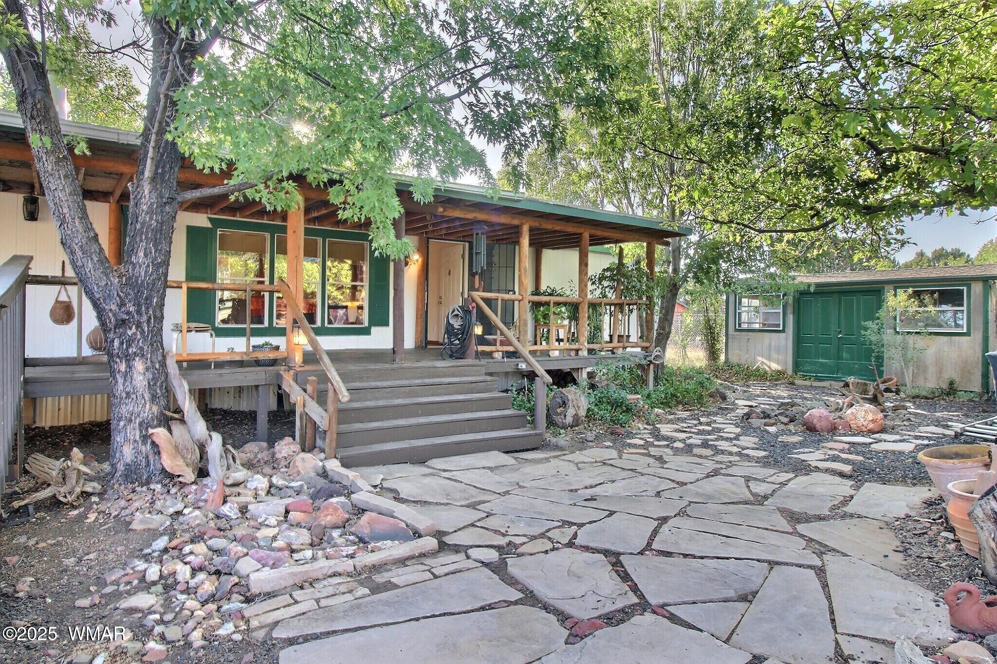 Local stones make up an outdoor sitting area covered by large shade trees.