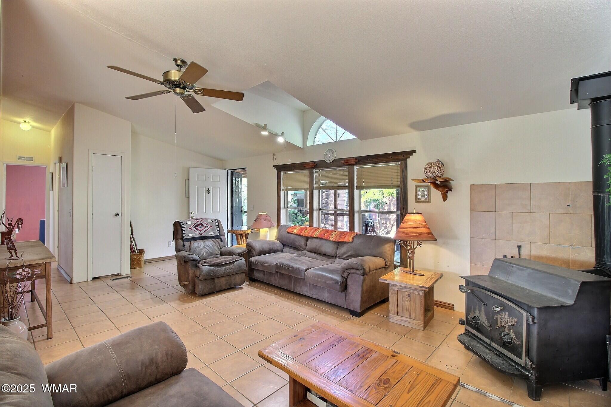 The living room features a large woodstove. Large picture windows look out on to the covered deck.