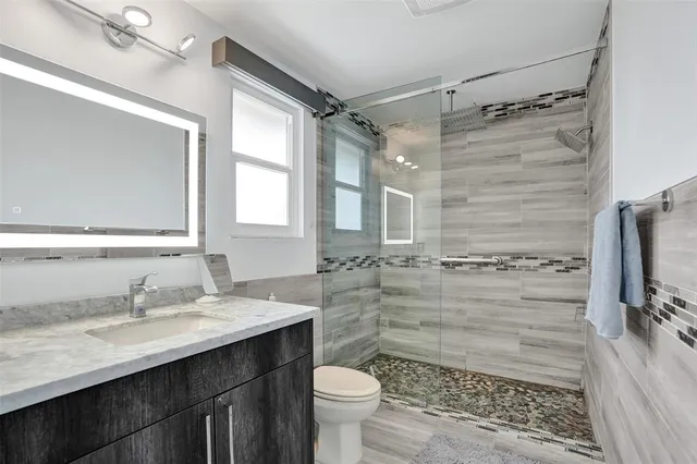 a bathroom with a sink toilet double vanity and shower