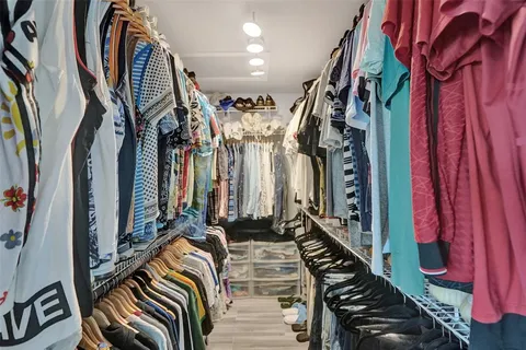 a view of walk in closet with clothes and shoes