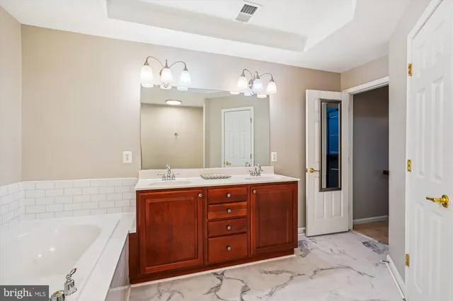 a spacious bathroom with a granite countertop double vanity sink a mirror and a bathtub