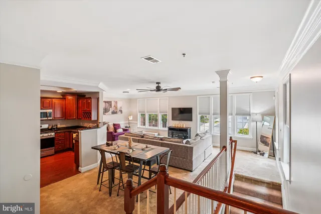 a open kitchen with stainless steel appliances kitchen island granite countertop a stove top oven a sink a dining table and chairs with wooden floor